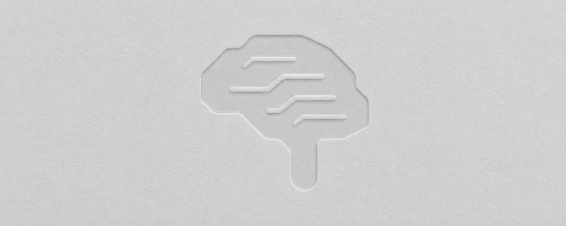 A brain icon with circuit-board style connections, blind-embossed on paper.