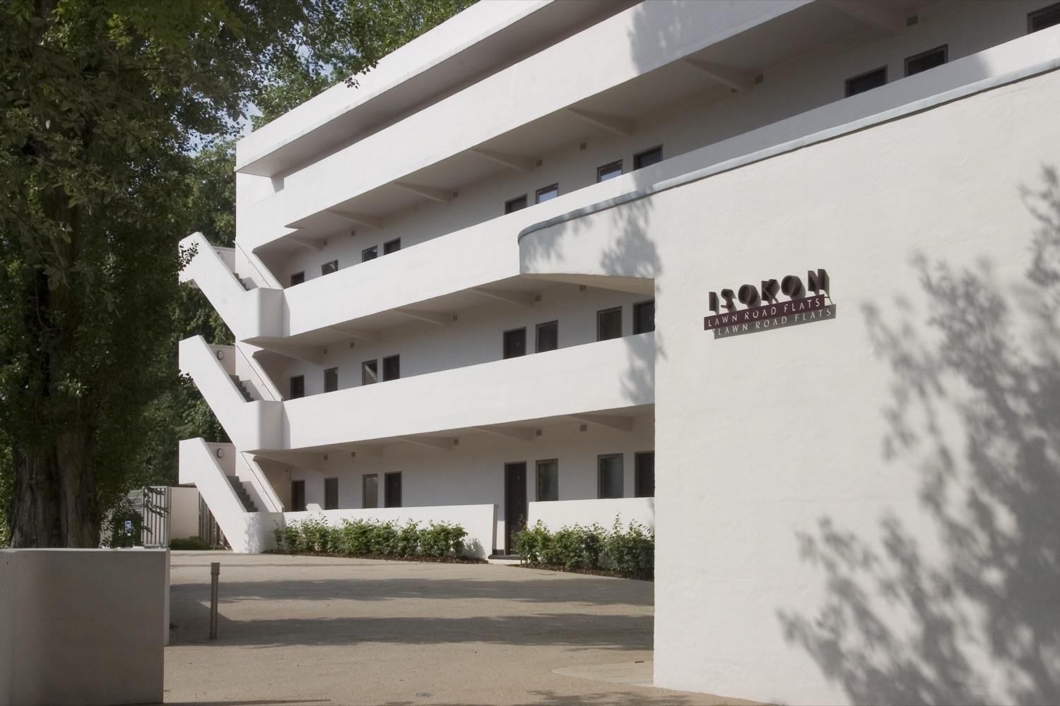 The white modernist Isokon building (Lawn Road Flats) with cantilevered access balconies, and raised cast lettering on the end wall reading &lsquo;Isokon &ndash; Lawn Road Flats&rsquo;.