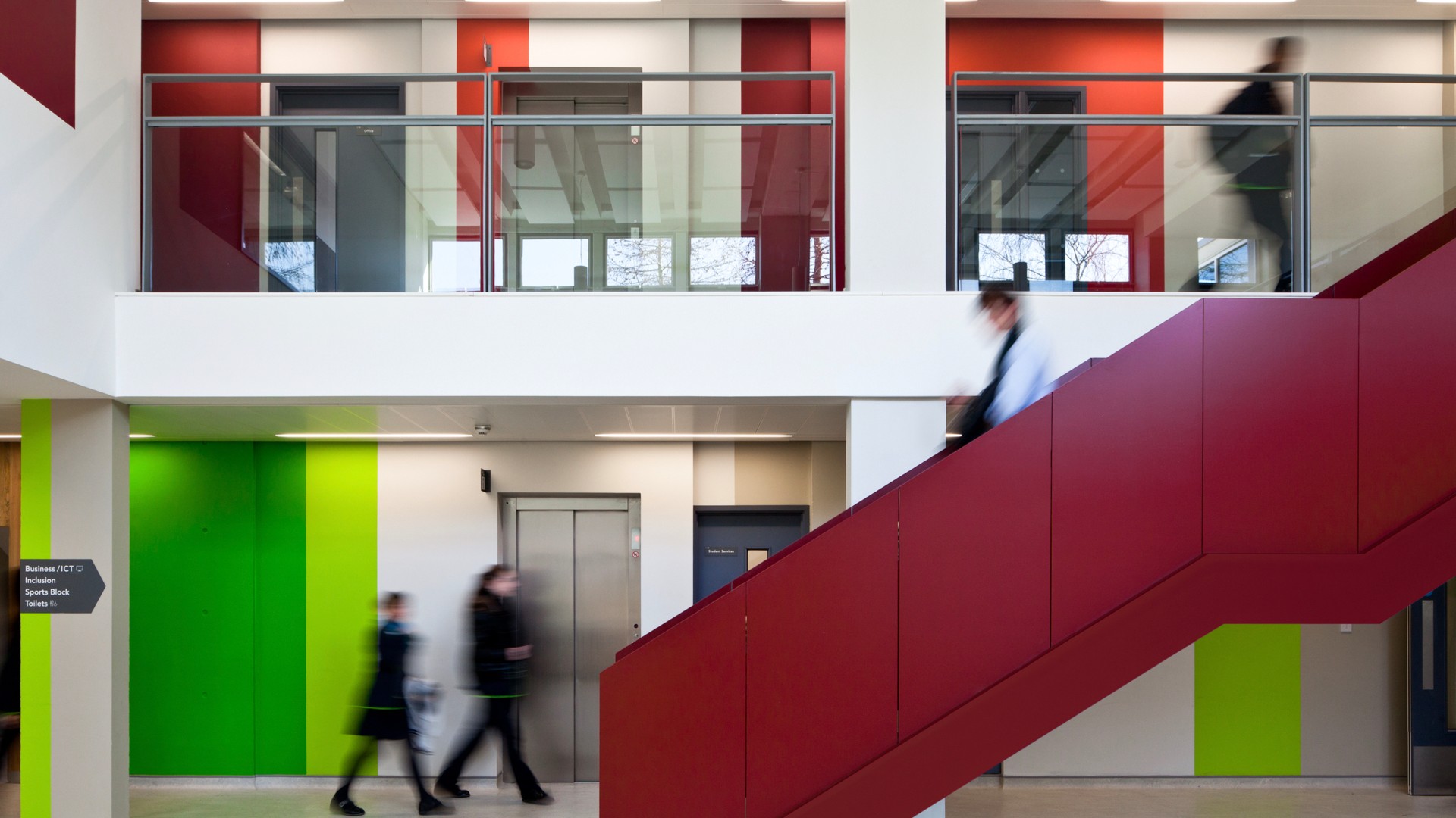 Interior of Haggerston School showing a staircase and corridor walls painted in bands of red and green to distinguish floors.